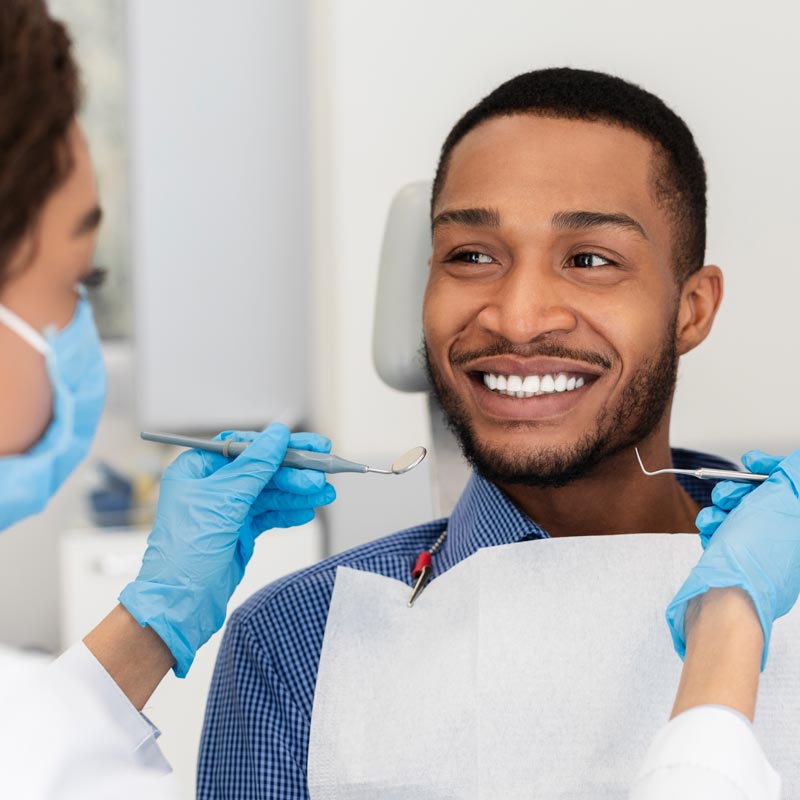 Smiling guy in dentist chair looking with trust at doctor