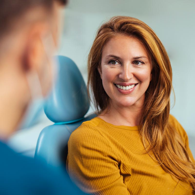 Smiling red haired woman listening to her dentist while sitting in his office