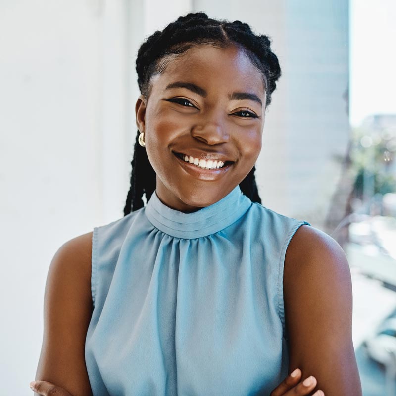 Confident young black businesswoman standing at a window in an office alone