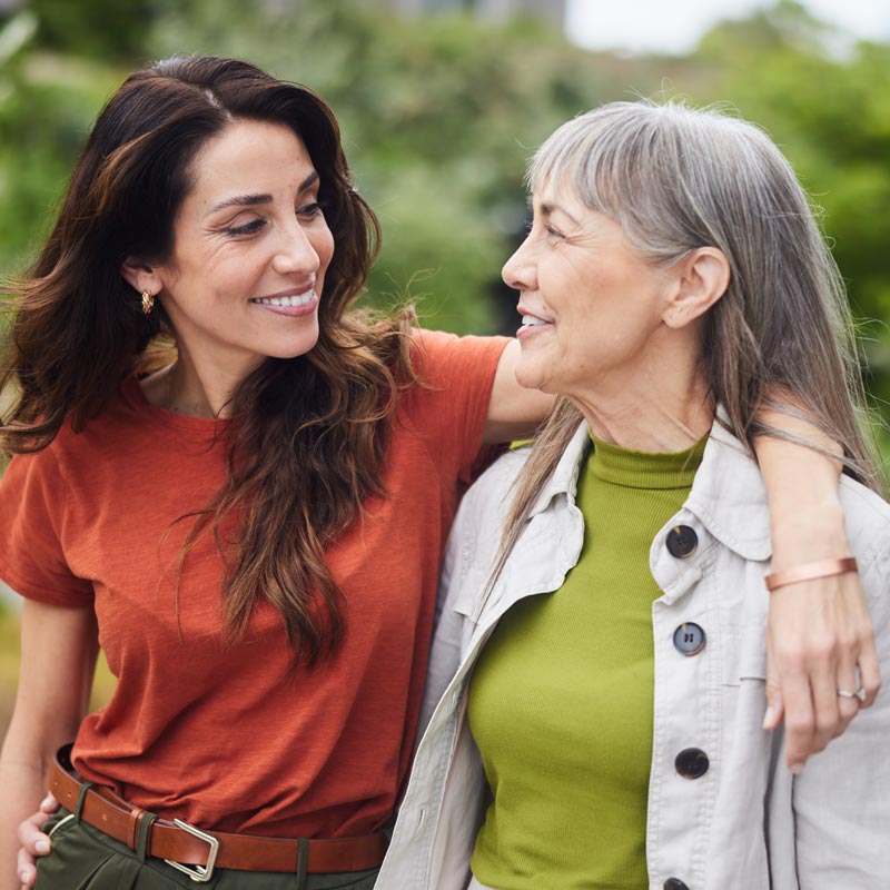 Smiling woman talking with her senior mom while walking outside